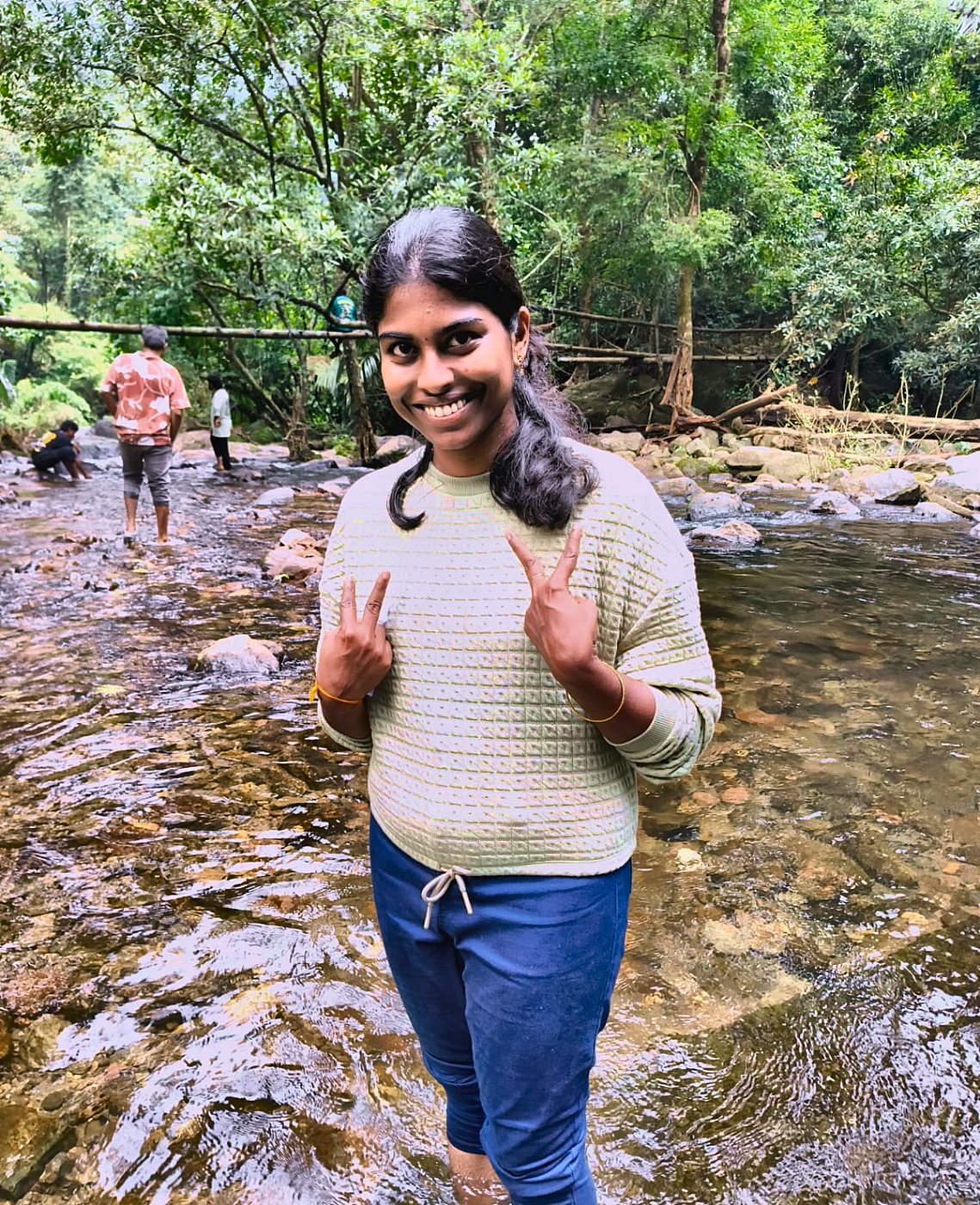 Kaviya standing in a stream showing peace signs