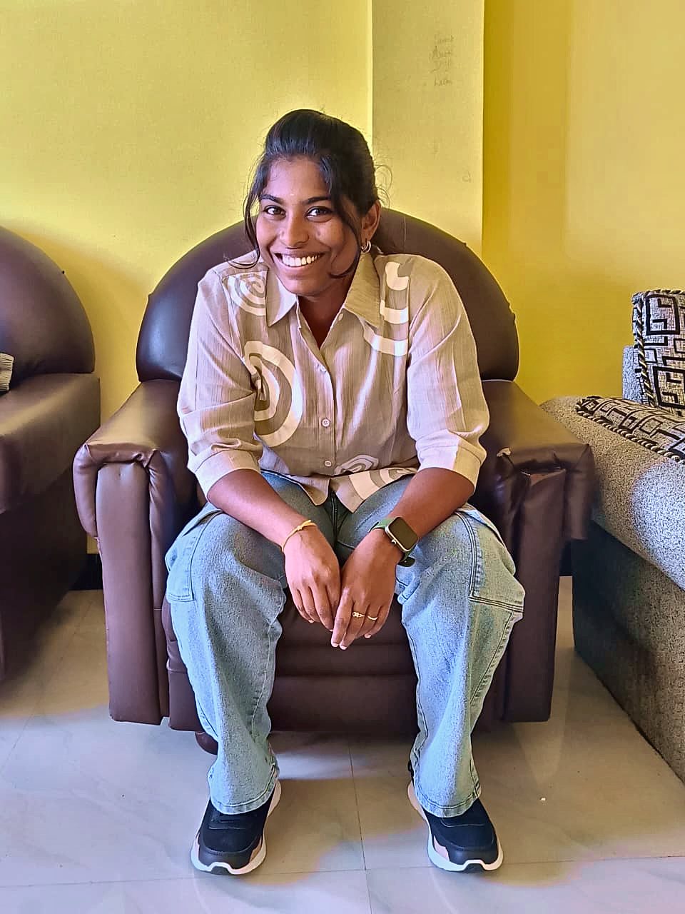 Kaviya smiling on a sofa