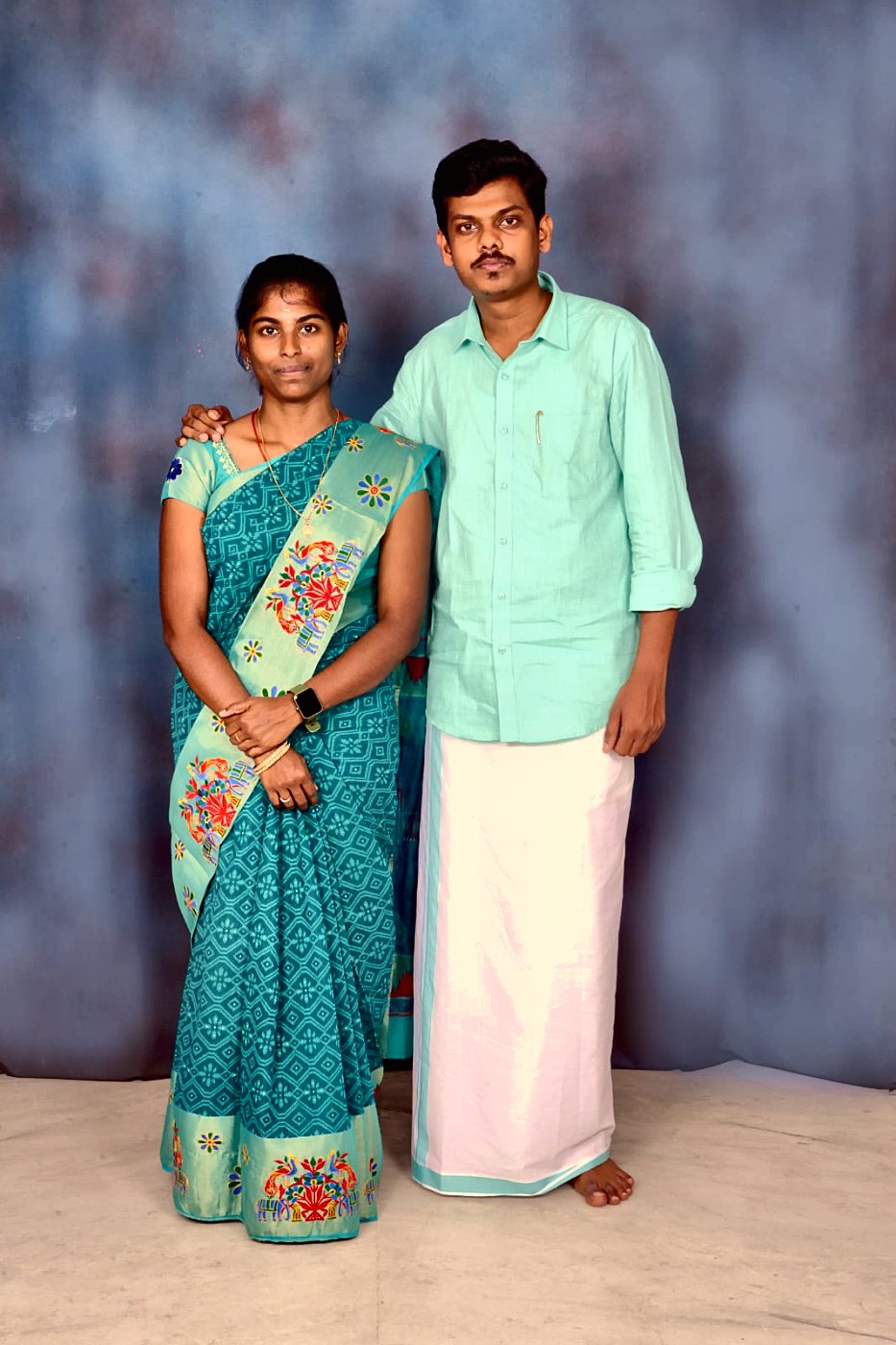 Kaviya in a teal saree and Prakash in a mint shirt and veshti, studio portrait